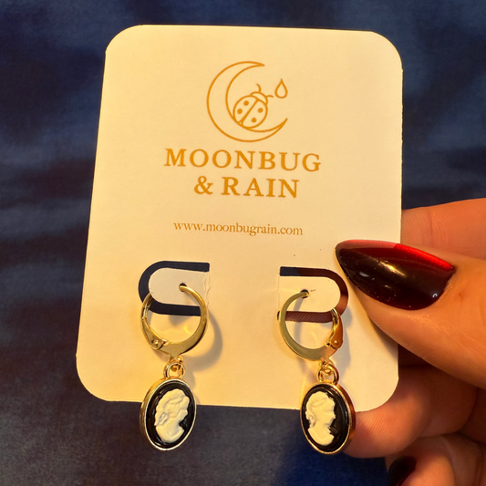 Cameo earrings on a Moonbug & Rain branded card against a dark background