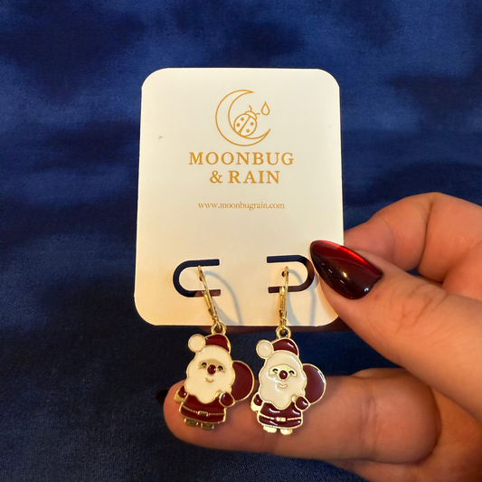 Santa Claus earrings on a 'Moonbug & Rain' card against a blue background