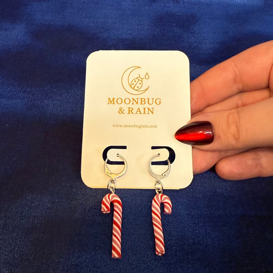 Candy cane earrings on a Moonbug & Rain card held against a blue background